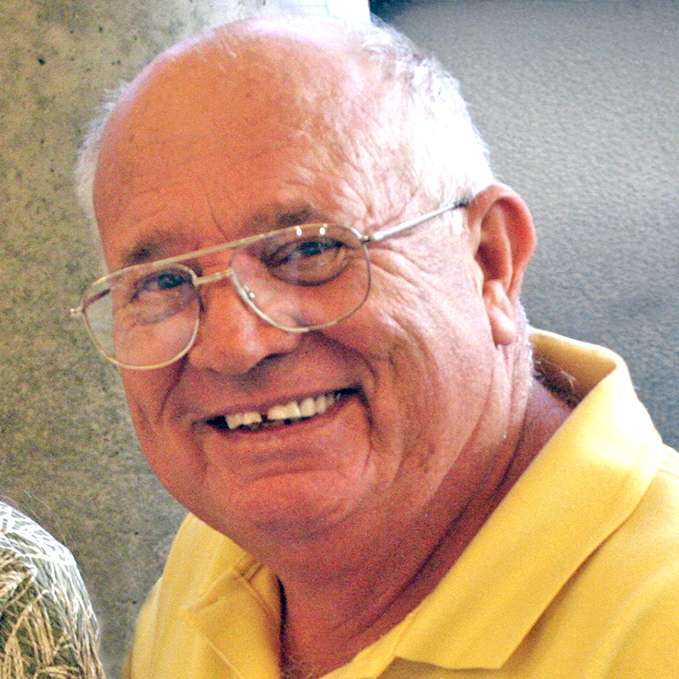 older man with glasses in a yellow polo shirt smiling