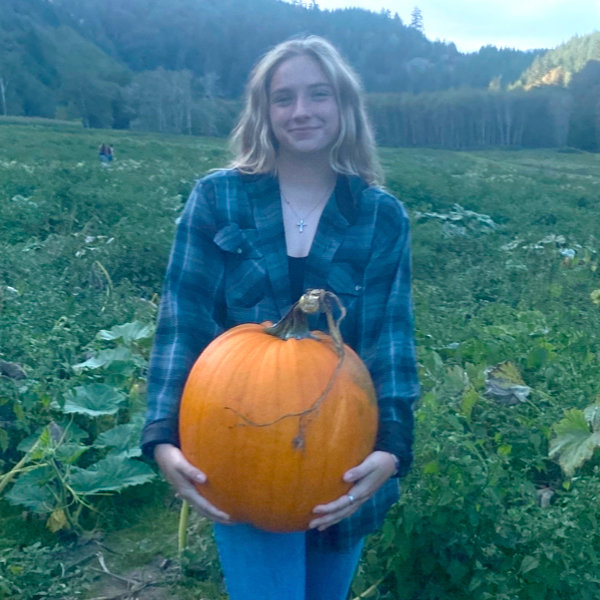 image of a young woman holding a pumpkin in a field