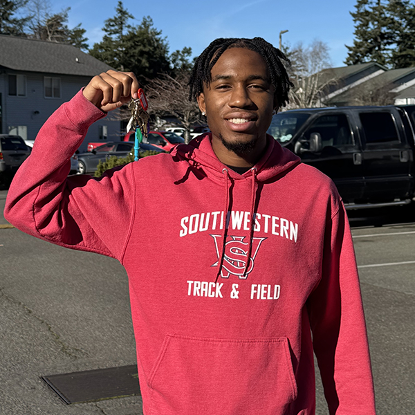 image of a young man smiling and holding up keys